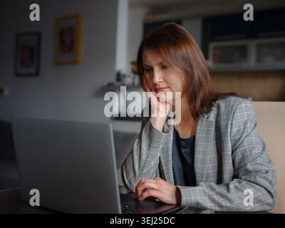 Frustrated sad woman feeling tired worried about problem sitting on sofa with laptop, stressed depressed girl troubled with reading bad news online, e Stock Photo