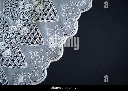 Lace pattern, detail of a tablecloth isolated on a black background. Artistic border. Handicraft, vintage. Hobby concept. Top view. High quality photo Stock Photo