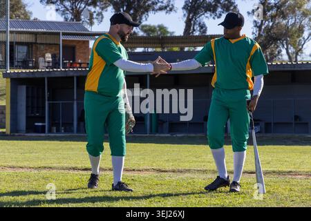 Two players on baseball field meeting hands signaling next play causing animated stats on bat glove Stock Photo