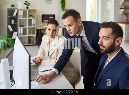 Business team analyzing data on computer in office, planning strategy together Stock Photo
