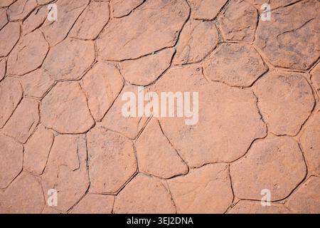 Sidewalk made of stamped concrete in an orange-brown color with an irregular stone pattern. Stock Photo