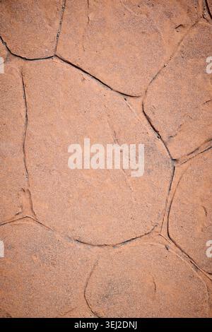Sidewalk made of stamped concrete in an orange-brown color with an irregular stone pattern. Stock Photo