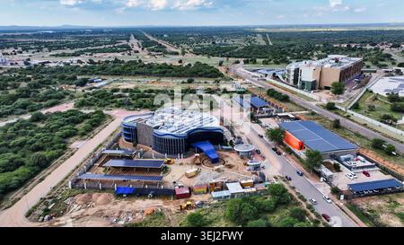 elevated perspective shows a contemporary curved office building featuring extensive solar-canopy parking and rooftop cooling systems within a develop Stock Photo