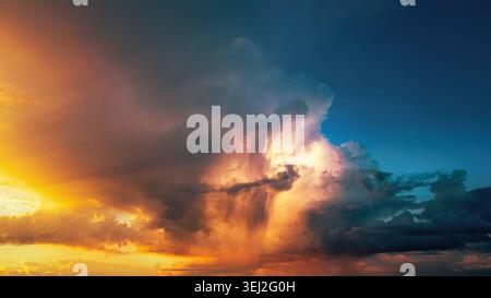 Dramatic storm clouds illuminated in vivid orange tones at sunset. A nature shot of a weather phenomenon. Stock Photo