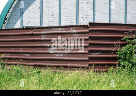Weathered metal fence with faded painted circles outdoors Stock Photo