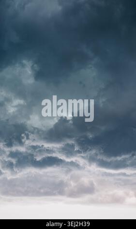Moody vertical storm clouds and dark dramatic sky. Dramatic vertical view of dark, ominous storm clouds gathering in a moody sky. Stock Photo