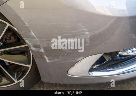 Close-up of deep scratches and scuffs on a gray car bumper near the wheel Stock Photo