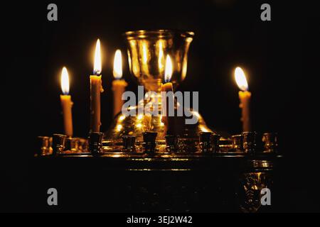 Burning memorial candles in church on dark background. Symbol of remembrance prayer faith spiritual reflection tribute and devotion. Stock Photo