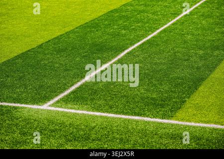 High-angle view of crisp white boundary lines on a green striped artificial grass football field  Stock Photo