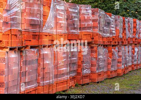 A large stack of orange perforated clay bricks. Stock Photo