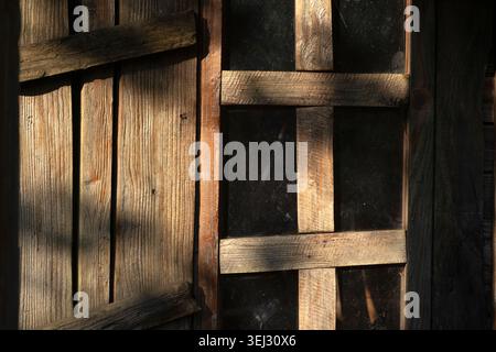 Old window with wooden slats and boarded up planks on an abandoned building Stock Photo