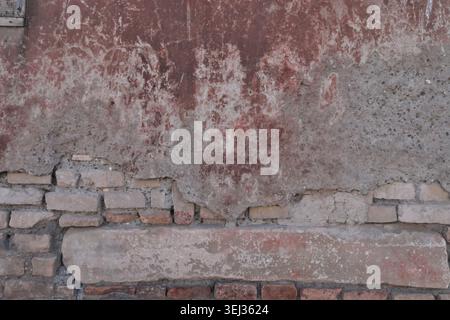 BACKGROUND TEXTURE OF AN OLD BRICK WALL WITH CRACKED PLASTER Stock Photo