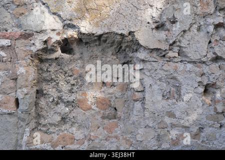 BACKGROUND TEXTURE OF AN URBAN STONE WALL WITH CRACKED PLASTER Stock Photo