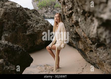 Woman posing on sandy beach between rocks Stock Photo