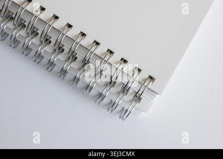Horizontal macro close up of spiral notebook binding on white surface in studio. Minimal stationery, modern publishing, elegant branding, creative Stock Photo