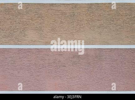 Abstract textured stucco wall background featuring soft pastel beige and pink horizontal sections divided by clean white stripes. Decorative wallpaper Stock Photo