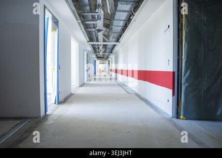 Elongated corridor under construction with exposed pipes and bright walls, Nagold hospital conversion, Calw district, Germany Stock Photo