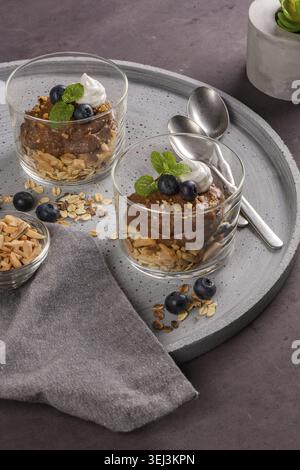 Glass cups of chocolate and chestnuts mousse with roasted almonds and oats decorated with black berries and mint leaves Stock Photo