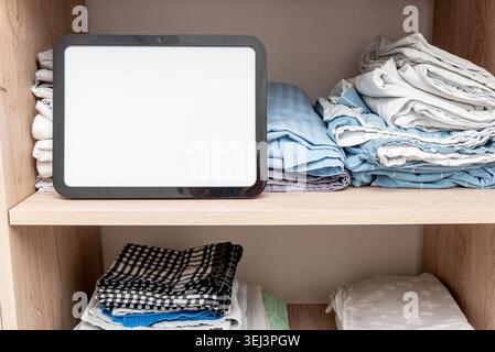 Blank empty white board notebook billboard with copy space for text on bed linen, sheets and pillowcases and towels neatly stacked in closet in bedroo Stock Photo