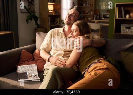 Couple Embracing on Sofa in Relaxed Home Lifestyle Stock Photo