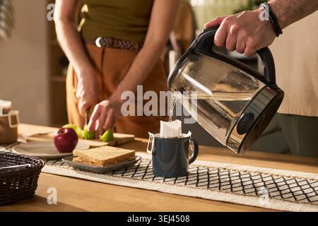 Adult Couple Preparing Breakfast and Pouring Tea at Home Stock Photo