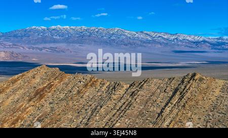 Aerial Rugged Desert Ridge and Snow Capped Mountains Under Blue Sky Stock Photo