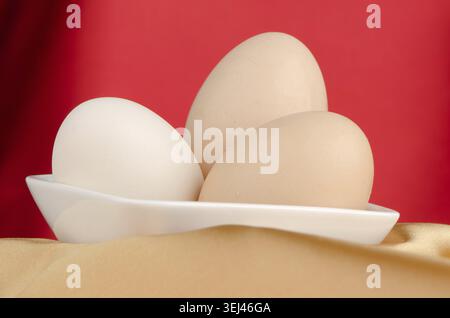 Eggs, Three eggs in the bowl on a red background Stock Photo
