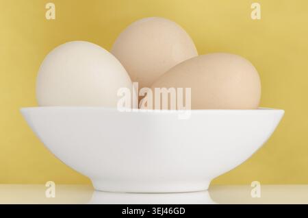 Eggs, Three eggs in the bowl on a yellow background Stock Photo