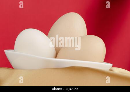 Eggs, Three eggs in the bowl on a red background Stock Photo