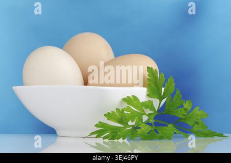 Eggs, Three eggs in the bowl on a blue background Stock Photo