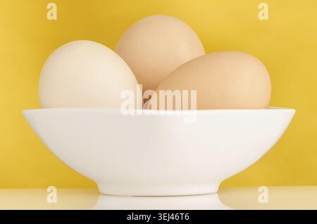 Eggs, Three eggs in the bowl on a yellow background Stock Photo