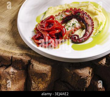 Food, A beautifully plated dish featuring grilled octopus over creamy mashed potatoes, garnished with red peppers and a drizzle of green sauce. Perfec Stock Photo