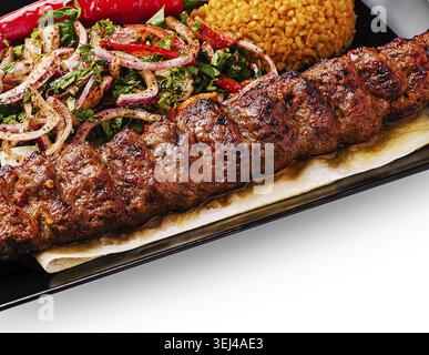Food, Tender kebab placed on a plate alongside seasoned rice and a colorful salad with onions and peppers. This meal showcases a mix of flavors popula Stock Photo