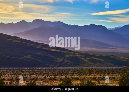 Layered Mountain Ridges at Sunset with Desert Valley Panorama and Dramatic Sky Stock Photo