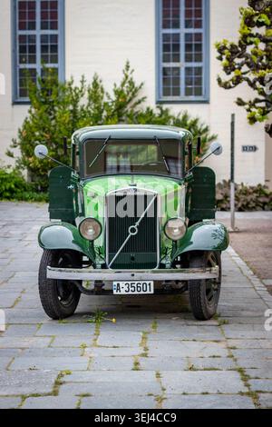 Front view of a classic vintage green Volvo truck parked on a paved courtyard Stock Photo