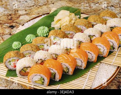 Food, A beautifully arranged platter of sushi showcasing a variety of rolls, including salmon and crunchy rolls, presented with wasabi and pickled gin Stock Photo