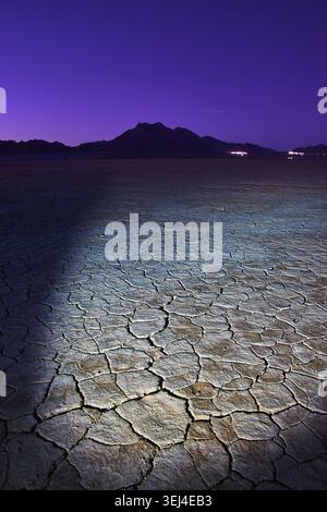 Cracked Dry Lake Bed at Twilight With Distant Nevada Mountains and Purple Sky Stock Photo