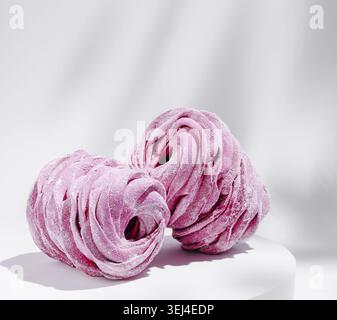 Food, Two swirled pink meringues sit neatly together on a light surface. Their vibrant color and delicate texture create an eye-catching display perfe Stock Photo