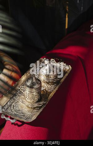 Food, Traditional oriental metal coffee set on a red fabric background. Antique engraved coffee cups and tray in warm light, luxury Middle Eastern dec Stock Photo