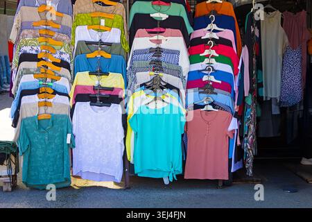 Colorful clothes on hangers sold on flea market outside Stock Photo