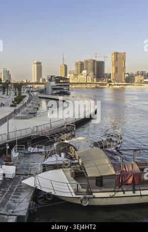 Caior, Egypt - February 4, 2026: A tranquil Cairo waterfront scene featuring a curved promenade, moored boats, and a bustling skyline with constructio Stock Photo