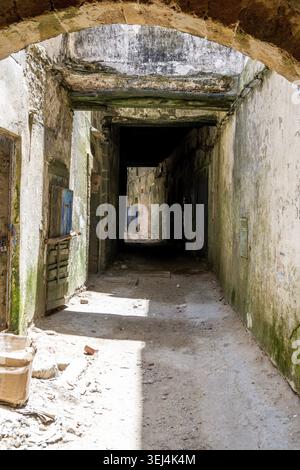 Dilapidated passage with gray and moss-covered walls in Essaouira Stock Photo