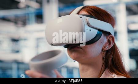 Data center female engineer uses VR glasses to manage enterprise cloud computing IT solutions. Software developer using virtual reality simulation to monitor server farm facility workspace, camera B Stock Photo