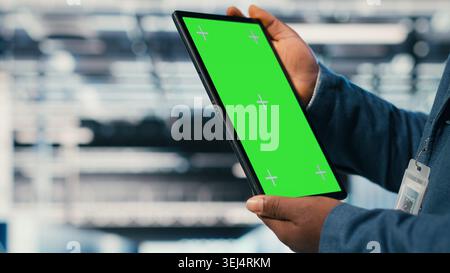 Green screen mockup tablet in server room used by worker to enhance hardware operational effectiveness. Data center engineer using chroma key isolated screen device to monitor gear, camera B close up Stock Photo
