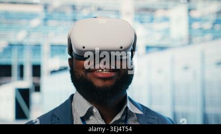 Doing machines maintenance, VR glasses equipment and employee in server hub finishing tasks. Configuring settings, virtual reality simulation tech and IT specialist in modern data center, camera B Stock Photo