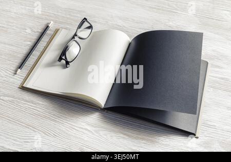 Mockup of opened blank booklet, pencil and glasses on light wooden background Stock Photo