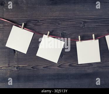 Blank photo frames attach to rope with clothespins on vintage wood background Stock Photo