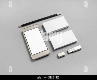 Cellphone and stationery on gray paper background. Blank business cards, pencil, smartphone and usb flash drive Stock Photo