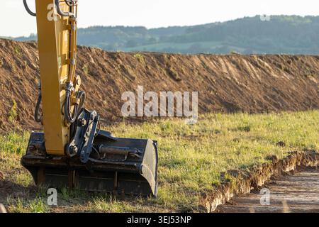 Excavator bucket at a construction site during earthmoving and land grading operations, heavy machinery working on infrastructure development project. Stock Photo