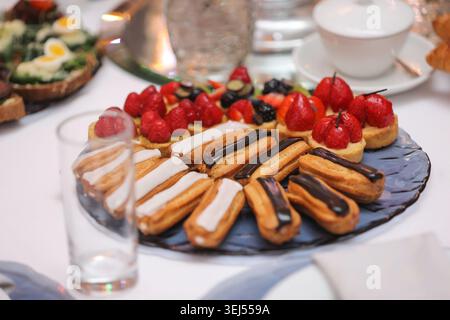 Mini Eclairs and Fruit Tarts on Dessert Platter Stock Photo